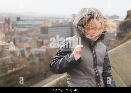 An einem windigen Wintertag in Edinburgh, Schottland, geblasen die Haare einer jungen Frau in alle Richtungen. Stockfoto