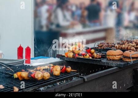 Saftige Fleischscheiben mit Sauce und Gemüse werden über einem offenen Feuer gekocht. Snacks werden auf einem Metallgrill zubereitet und bereit zum Seren. Selektiver Fokus Stockfoto