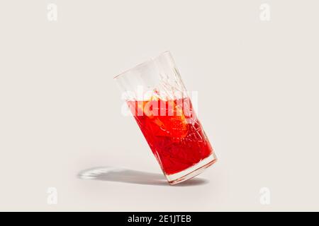 Ein gekipptes Glas roten Wermut auf grauem Hintergrund Stockfoto