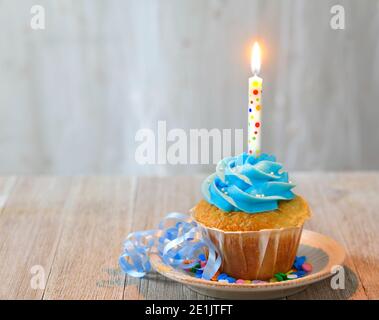 Cupcake mit Kerze und blauem Zuckerguss zum Geburtstag Stockfoto
