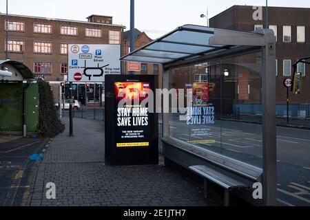 Die Regierung von HM und die NHS-Werbetafeln raten, zu Hause zu bleiben und dabei zu helfen, Leben an einer Bushaltestelle während der dritten nationalen Coronavirus-Sperre im Stadtzentrum von Birmingham zu retten, die außer einigen wenigen Menschen am 7. Januar 2021 in Birmingham, Großbritannien, verlassen ist. Nach dem jüngsten Anstieg der Fälle, darunter die neue Variante von Covid-19, ist diese landesweite Sperre, die eine effektive Tier fünf ist, gestern in Betrieb genommen worden, wobei alle Bürger der Botschaft folgen sollten, zu Hause zu bleiben, den NHS zu schützen und Leben zu retten. Stockfoto