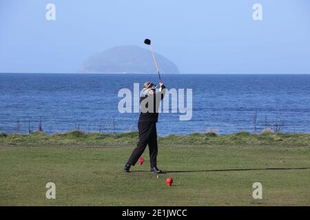 Städtischer Golfplatz Girvan, Ayrshire, Schottland, Großbritannien. Golferin auf dem ersten T-Shirt mit Ailsa Craig im Hintergrund Stockfoto