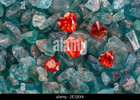 Rote herzförmige Diamanten sind auf rohen himmelblauen Edelsteinen. Stockfoto