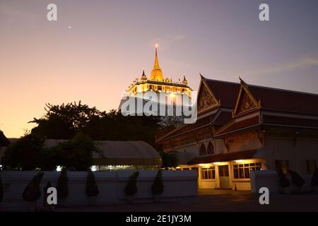 Buddhistischer Tempel Goldener Berg (Wat Saket) in Bangkok beliebtes Reiseziel in Thailand. Beleuchtetes goldenes Gebäude auf dem Hügel zur Abendzeit Stockfoto