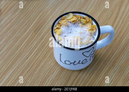 Eine Tasse Milch und Cornflakes isoliert auf Holztisch. Gesundes Frühstück. Draufsicht. Stockfoto