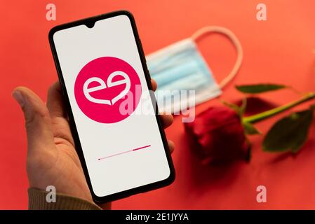 London, Großbritannien - 6. januar 2021: Nahaufnahme des meetic Dating App-Logos auf dem Handy mit roter Rose und Covid-Gesichtsmaske. Konzept der Online-Dating während der cor Stockfoto