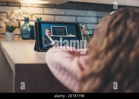 Rückansicht Foto von einem kleinen Mädchen mit Online-Unterricht Verwenden eines Tablets zur Ferninteraktion mit dem Lehrer Stockfoto