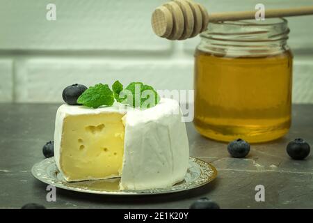 Frischer Honig und Camembert Käse Nahaufnahme mit Platz für Text. Camembert in Schichten mit Trauben und Bienenhonig geschnitten Stockfoto