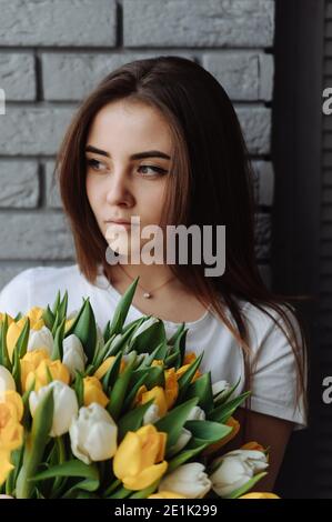 Junges Mädchen mit Blumenstrauß in der Hand. Frau mit Tulpen. Internationaler Frauentag Stockfoto