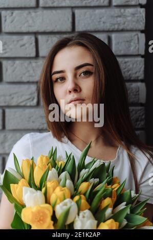 Porträt des Mädchens mit Blumenstrauß aus weißen und gelben Tulpen. Frau mit Tulpen. Internationaler Frauentag Stockfoto