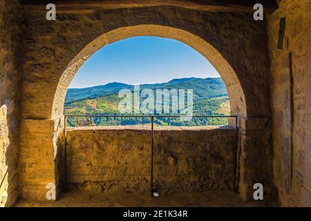 Ein teilweise blockierter Bogen mit Blick auf die nahe gelegene Landschaft im historischen mittelalterlichen Dorf Santa Fiora in der Provinz Grosseto, Toskana, Italien Stockfoto