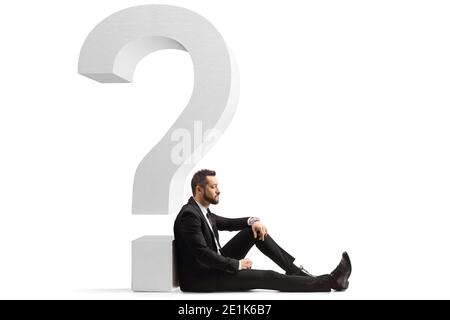 Trauriger Geschäftsmann, der auf dem Boden saß und sich auf einen lehnte Fragezeichen isoliert auf weißem Hintergrund Stockfoto