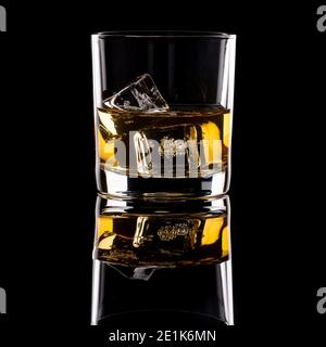 Seitenansicht von Whiskey in einem Tumbler mit Eiswürfeln, reflektiert auf einem glänzend schwarzen Hintergrund Stockfoto