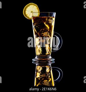 Eistee mit einer Zitronenscheibe in einem hohen Glas Mit Griff auf schwarzem Hintergrund Stockfoto
