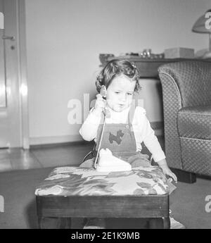 1950er niedliche Mädchen Kleinkind spielt mit Spielzeug Telefon, USA Stockfoto