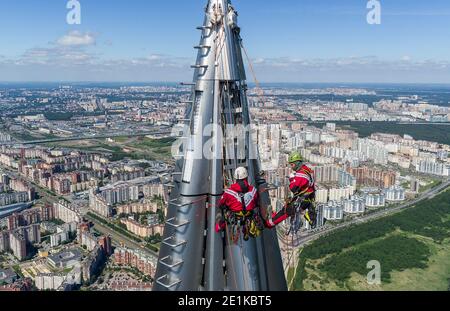 Arbeiter Installateure in der Höhe arbeiten an der Spitze des Wolkenkratzers. Stockfoto