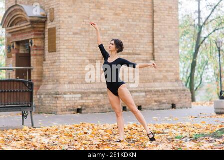 Schöne Hündin, Ballerina, Athlet im schwarzen Bodysuit Training im Park Stockfoto