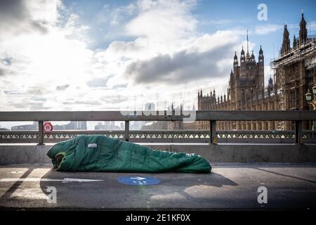 Ein rauer Schläfer in seinem Schlafsack während der Mittagszeit auf der Westminster Bridge, London, Großbritannien. Stockfoto