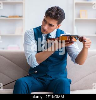 Der junge Musiker Mann spielen Geige Üben zu Hause Stockfoto