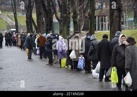 Lviv, Ukraine. Januar 2021. Menschen mit Gesichtsmasken stehen in einer Reihe während der Verteilung von kostenlosen Lebensmitteln und Weihnachtspakete für Weihnachten in Lemberg.in der Ukraine, die meisten Menschen feiern Weihnachten auf dem Julianischen Kalender. An diesem Tag verteilt die Organisation 'Emmaus - Haus' Lebensmittel- und Weihnachtspakete für Obdachlose und Menschen mit geringem Einkommen. Kredit: SOPA Images Limited/Alamy Live Nachrichten Stockfoto