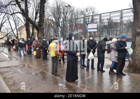 Lviv, Ukraine. Januar 2021. Menschen mit Gesichtsmasken stehen in einer Reihe während der Verteilung von kostenlosen Lebensmitteln und Weihnachtspakete für Weihnachten in Lemberg.in der Ukraine, die meisten Menschen feiern Weihnachten auf dem Julianischen Kalender. An diesem Tag verteilt die Organisation 'Emmaus - Haus' Lebensmittel- und Weihnachtspakete für Obdachlose und Menschen mit geringem Einkommen. Kredit: SOPA Images Limited/Alamy Live Nachrichten Stockfoto