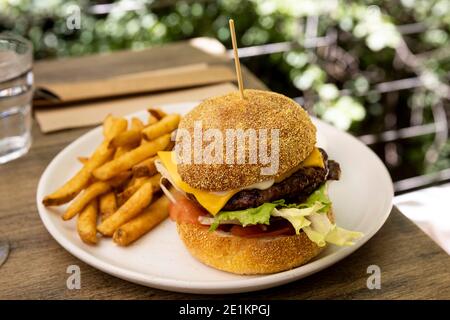 Ein köstlicher Cheeseburger und Pommes auf einem Tisch im Freien serviert Stockfoto