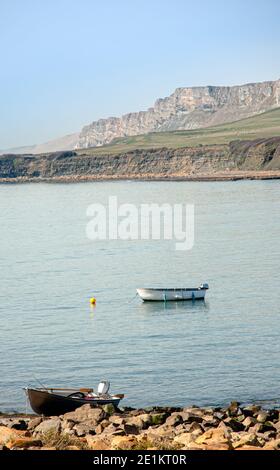 ISLE OF PURBECK, DORSET, Großbritannien - 16. MÄRZ 2009: Kleines Schlauchboot, das in der Kimmeridge Bay vor Anker liegt, mit einem anderen Schlauchboot an der felsigen Küste im Vordergrund Stockfoto