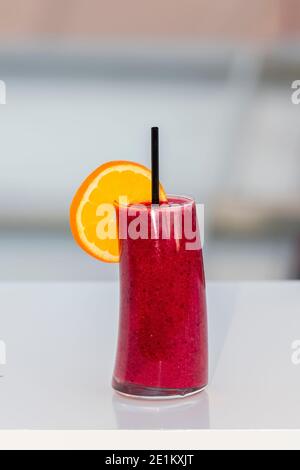 Köstlich aussehende Beeren Cocktail mit einer orangen Scheibe auf einem Tisch auf einem unscharf Hintergrund. Nahaufnahme. Freizeit- und Lifestyle-Konzept. Stockfoto