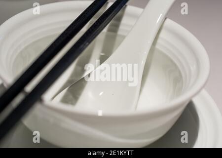 Schwarze Essstäbchen, Löffel und Geschirr auf dem Tisch für chinesisches Essen Stockfoto