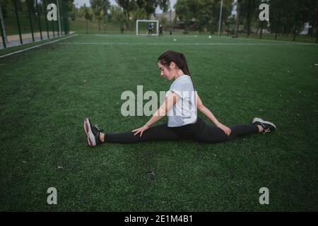 Junge Frau tun das Training Split Bein spielt Sport in Der Park außerhalb Spielplatz Stockfoto