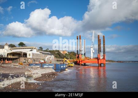 Wave Walker Jack-up Barge hilft beim Bau einer neuen größeren Meeresmauer in Dawlish zum Schutz der Eisenbahn, Devon, England. Stockfoto