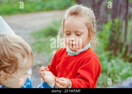 Schwester spielt mit ihrem Bruder im Kinderwagen, rollt das Baby die Straße hinunter Stockfoto