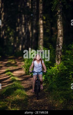 Kinder Mädchen Fahrrad fahren im Freien im Wald lächelnd. Stockfoto