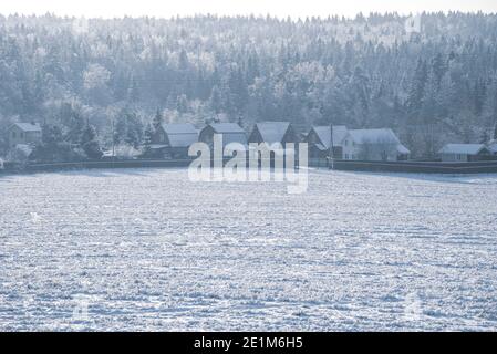 Ein schneebedecktes Dorf am Rande eines weiten Feldes. Stockfoto