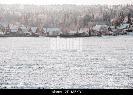 Ein schneebedecktes Dorf am Rande eines weiten Feldes. Stockfoto