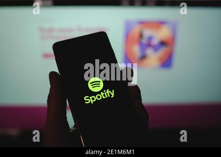 Mann, der ein Smartphone mit Spotify-Logo vor sich hält Die offizielle Website Stockfoto