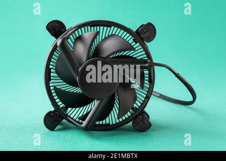Computer-CPU-Lüfter Kühler auf seiner Seite über einem türkisblauen grün strukturierten Hintergrund. Wartung und Reparatur von Desktops. PC-Hardwarekomponente. Stockfoto