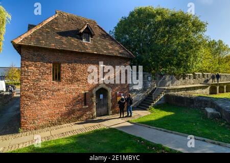 Touristen stehen und fotografieren C15 Red Tower & Paar Spaziergang auf sonnenbeleuchteten mittelalterlichen Barmauern - historische Sehenswürdigkeiten in York, North Yorkshire, England, Großbritannien. Stockfoto