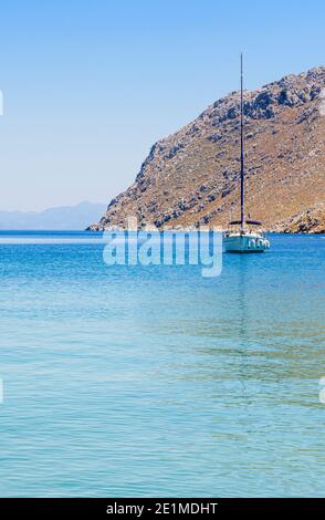 Yacht vor Anker in den ruhigen Gewässern der Pedi Bay, Symi Island, Dodekanes, Griechenland Stockfoto