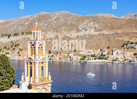 Der Glockenturm der Verkündigung-Kirche mit Blick auf die Südseite des Hafens von Gialos, Symi Island, Dodekanes, Griechenland Stockfoto