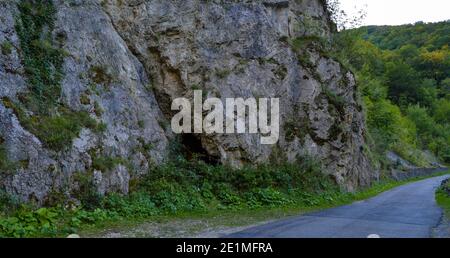 Sonne scheint über grüne üppige Vegetation und Straße durch felsige erodierte Gelände, Sohodol Gorges (Cheile Sohodolului), Valcan Berge, in Gorj County, Ro Stockfoto