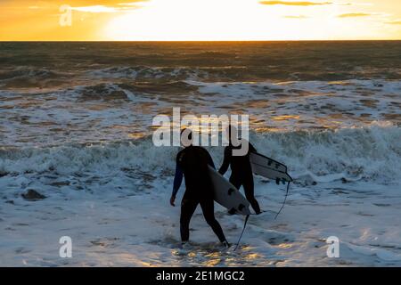 England, East Sussex, Eastbourne, Birling Gap, The Seven Sisters Cliffs and Beach, Two Male Surfers Walking on Beach mit Surfbrettern Stockfoto