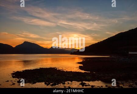 Sonnenaufgang über Langfjorden. Silhouetten von Bergen vor dem Hintergrund des dramatischen Himmels. Fjordlandschaft Norwegen Stockfoto