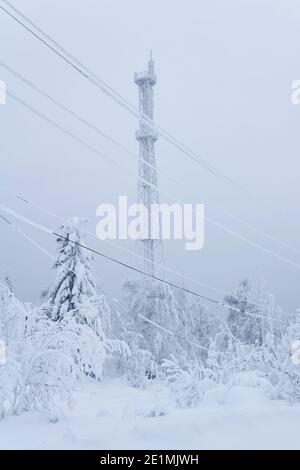 Eisbedeckte Zelle Turm über einem verschneiten Wald auf Ein Berg gegen einen Winterhimmel Stockfoto