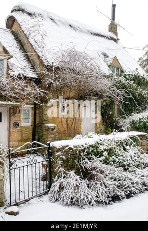 Cotswold Stein Reetgedeckten Hütte im Dezember Schnee. Taynton, Cotswolds, Oxfordshire, England Stockfoto