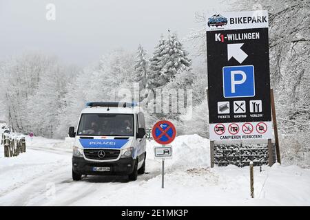 Willingen, Deutschland. Januar 2021. Polizeibeamte stehen mit einem Fahrzeug vor dem Eingang zu einem geschlossenen Parkplatz. Im Wintersportort gilt ab diesem Freitag aufgrund der Corona-Pandemie ein Verbot des Eintritts in die Skipisten und Rodelbahnen. Ausgelöst wurde das Verbot durch die Situation am vergangenen Wochenende: Nachdem die Wintersportregion Winterberg im benachbarten Nordrhein-Westfalen Pisten und Parkplätze gesperrt hatte, waren Tausende Ausflügler nach Nordhessen geschwommen. Quelle: Uwe Zucchi/dpa/Alamy Live News Stockfoto