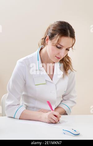 Junger Arzt am Arbeitsplatz sitzen und schreiben Stockfoto