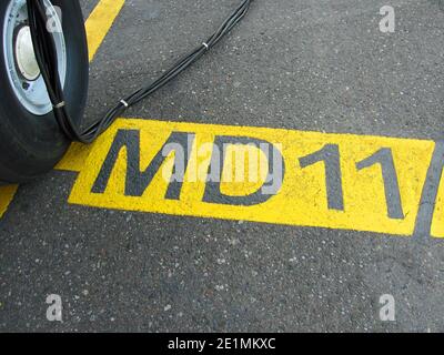 Nasenfahrwerk eines McDonnell Douglas MD11-Flugzeugs im Stehen Am Flughafen auf dem gelb markierten Parkplatz Farbe mit einem schwarzen Kabel Stockfoto