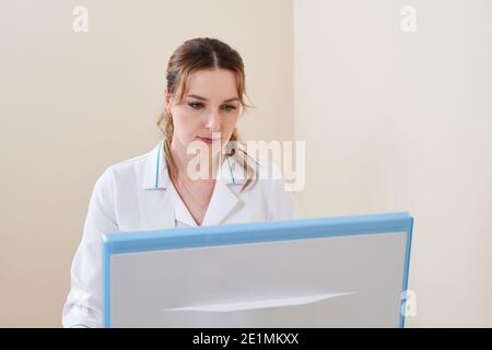 Porträt einer jungen professionellen Ärztin in der Klinik. Nahaufnahme eines Medikaments im Krankenhaus mit Computer Stockfoto
