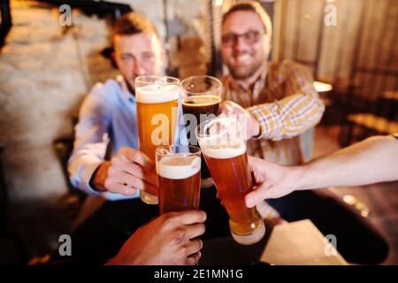 Eine Gruppe von Freunden, die im Pub anstoßen. Selektiver Fokus auf Bier. Stockfoto